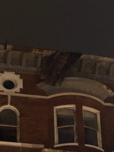 Debris dangles over rooftop, downtown Quincy